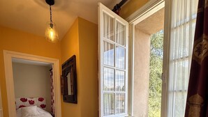A cozy room with a wooden bench, a bed with floral bedding, and a window with curtains.