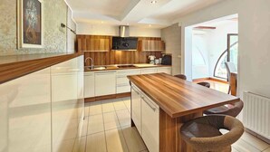 Une cuisine moderne avec des meubles en bois, une cuisinière encastrée et un coin repas comprenant une table en bois et deux chaises.