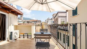 A terrace with a table and chairs, an air conditioning unit, and storage bins. - La Terrazza su Brescia · Panoramic terrace (Brescia)