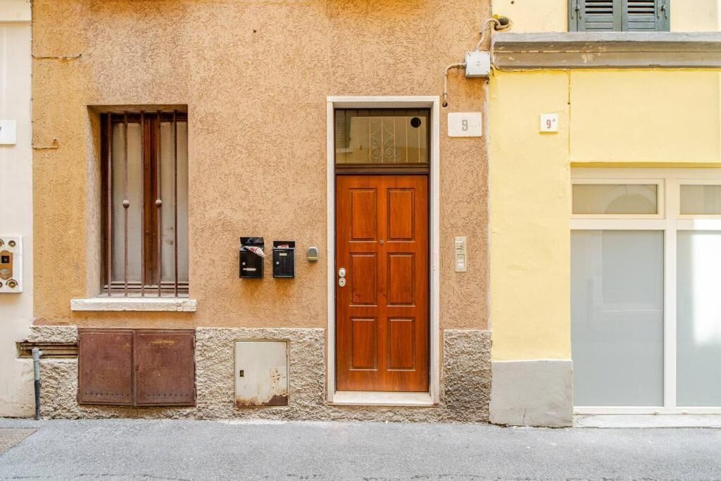 Un bâtiment avec une porte en bois, une fenêtre avec des barreaux en métal et une boîte aux lettres.