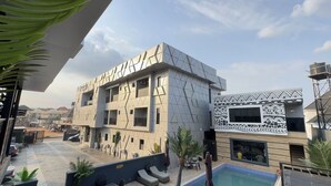 A modern building with geometric patterns, a pool area, and a clear sky. - Fullbliss Hotel and suites (Asaba)
