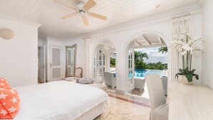A bedroom with a large bed, a ceiling fan, and a view of an outdoor swimming pool. - Waterfalls - 6 bed Peaceful and Secure Luxury (Westmoreland)