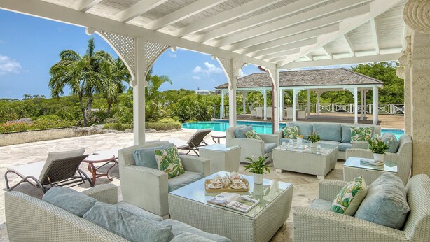 A covered outdoor seating area with wicker furniture, a pool, and a gazebo in the background. - Waterfalls - 6 bed Peaceful and Secure Luxury (Westmoreland)