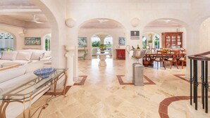 A spacious living area with a sofa, a glass coffee table, a dining table with chairs, and a chandelier. - Waterfalls - 6 bed Peaceful and Secure Luxury (Westmoreland)