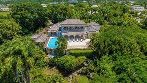 A large, multi-story house with a swimming pool, surrounded by lush greenery and other houses in the background. - Waterfalls - 6 bed Peaceful and Secure Luxury (Westmoreland)