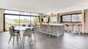A modern kitchen with a large island, bar stools, and a dining area with chairs. - Le Couvent des Ursulines - Appt climatisé, piscine (Narbonne)