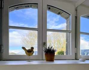 A room with large windows, a small bird figurine, and a potted plant.