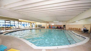 Une piscine intérieure dotée de chaises longues et d’un espace aménagé en véranda.