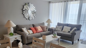 Un coin repas avec une table dressée pour quatre personnes, un canapé gris et un élément décoratif mural.