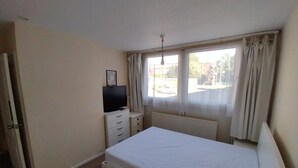 A bedroom with a bed, a TV on a dresser, and a window with curtains. - Lovely Double Bedroom - Putney (London)