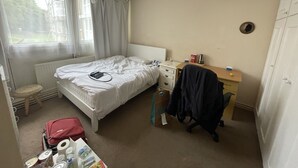 A small, clean room with a single bed, a bedside table, a chair, and a desk. - Lovely Double Bedroom - Putney (London)