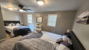 Ein Schlafzimmer mit zwei Betten, einem Deckenventilator und zwei Fenstern mit Jalousien.