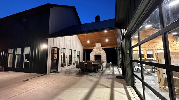 A modern building with a stone fireplace, large windows, and a patio area with outdoor seating. - The Reserve at Kirby Landing (Kirby)
