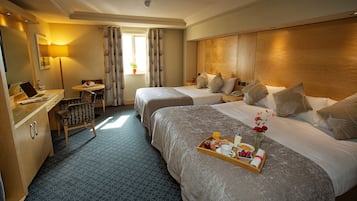 Habitación de hotel con dos camas, un escritorio con una computadora portátil, una bandeja con artículos de desayuno y una ventana con cortinas.