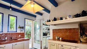 A kitchen with a central island, white cabinets, a tiled backsplash, and a blue ceiling. - Villa Gardelina (Corsica)