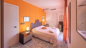 Une chambre d’hôtel avec un lit, des tables de chevet, une commode, une lampe et une porte.