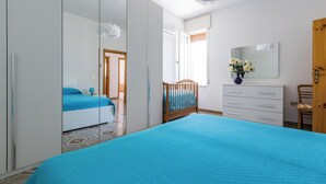 Une chambre avec un grand lit, une armoire, une commode et un berceau.