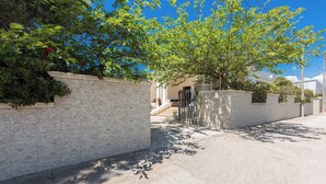 Un quartier résidentiel avec une allée pavée, un mur en briques et un arbre qui offre de l’ombre.