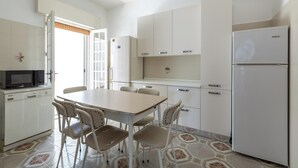 Une cuisine compacte avec des meubles blancs, un four à micro-ondes, un réfrigérateur et une table à manger avec des chaises.