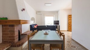 Un coin repas avec une table et des chaises, une cheminée en briques, un canapé et un téléviseur en arrière-plan.