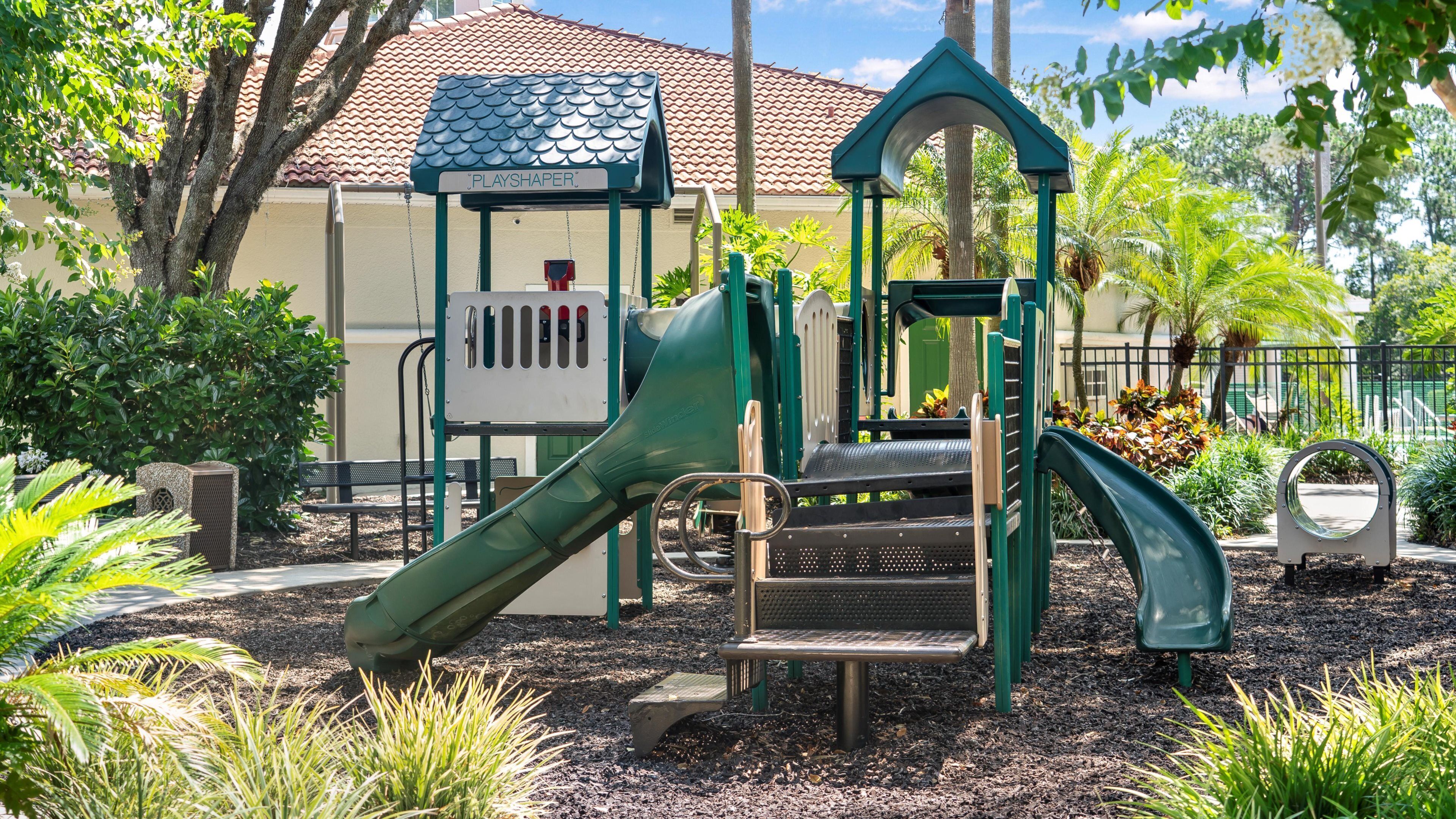 A playground with a slide, climbing structures, and a playhouse.