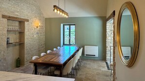 A spacious dining area with a long wooden table, stone walls, and a large mirror.