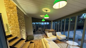 A modern interior with a staircase, wooden flooring, a sofa, armchairs, and a glass door leading outside.