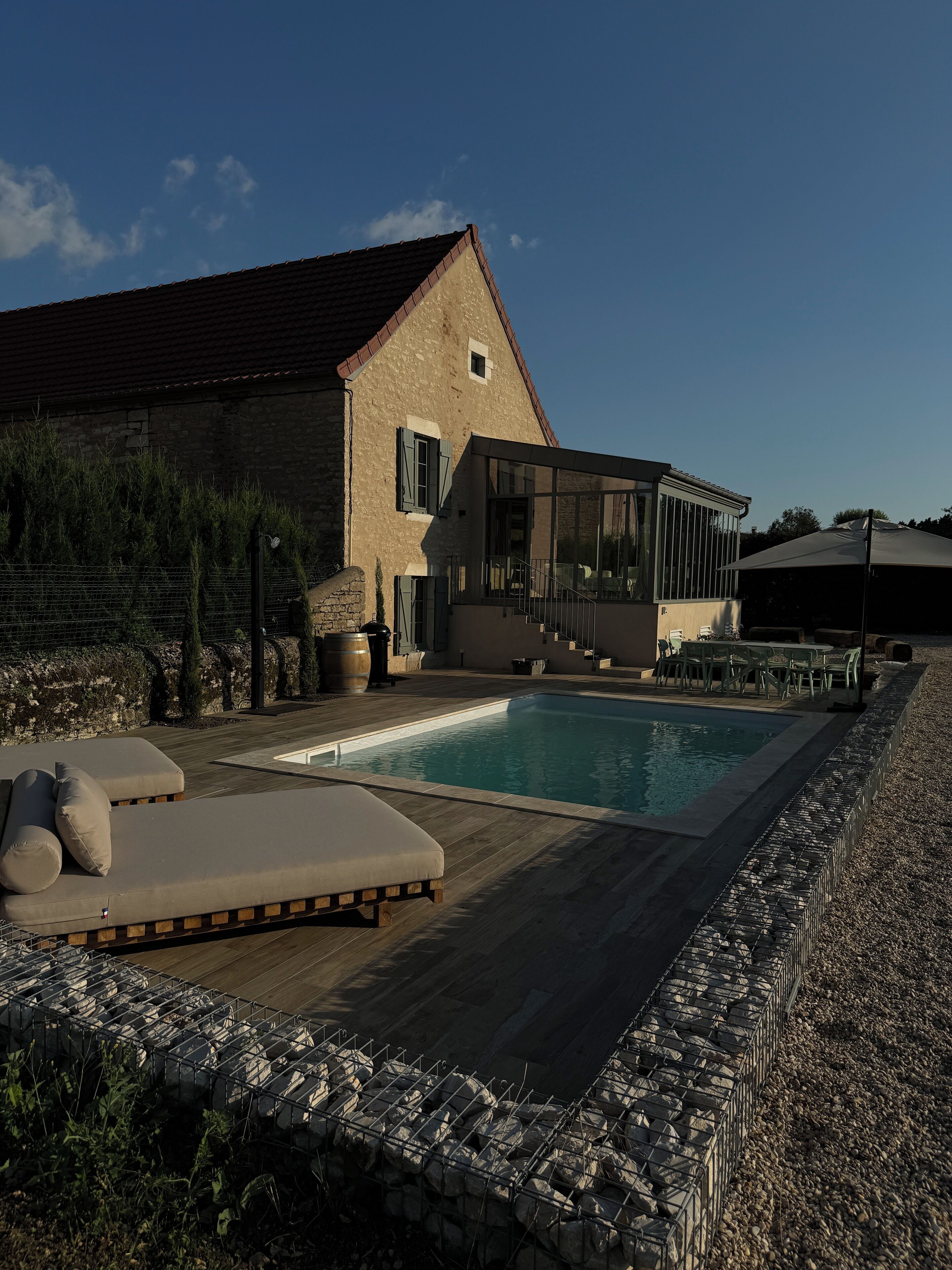 Ett modernt hus med en swimmingpool, en uteplats och en stenmur.