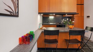 A modern kitchen with wooden cabinets, a granite countertop, and a central island with two chairs. - Santa Margherita Apartment in the city (Santa Margherita Ligure)