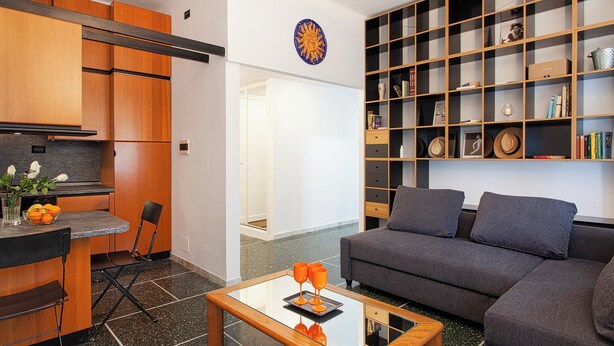 A modern living room with a grey sofa, a coffee table, and a bookshelf filled with books and decorative items. - Santa Margherita Apartment in the city (Santa Margherita Ligure)