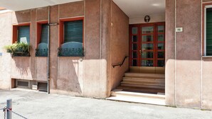 A building with a red door, a staircase leading to the entrance, and a small bench outside. - Santa Margherita Apartment in the city (Santa Margherita Ligure)