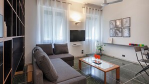 A modern living room with a sofa, a coffee table, a TV, and a ceiling fan. - Santa Margherita Apartment in the city (Santa Margherita Ligure)