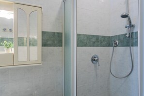 Et badeværelse med brusekabine i glas, toilet og vask med spejl.