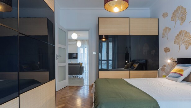 Una camera da letto moderna con un letto, un'area salotto e vista sulla città.