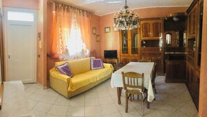 A dining area with a yellow sofa, wooden dining table, and chairs. - 75sqm apartment in villa (Cinisello Balsamo)