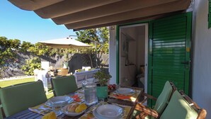 An outdoor dining area with a table set for two, chairs, and a green door.