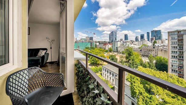 A balcony with a view of a cityscape, including modern buildings and construction cranes. - Warsaw Central Apt - 9th Floor, Balcony, Tram&Bus - by Rentujemy (Warszawa)