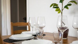 A dining table set with plates, glasses, and cutlery, a small plant, and a glass container with a plant. - Warsaw Central Apt - 9th Floor, Balcony, Tram&Bus - by Rentujemy (Warszawa)