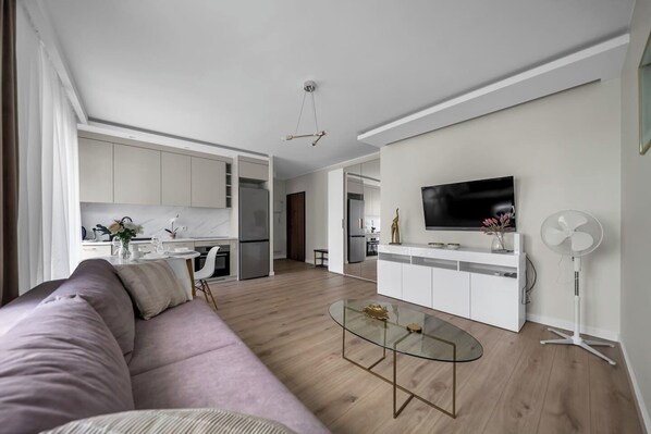 Relax in this open living space with a comfortable sofa, flat-screen TV, and modern kitchen.
