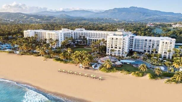 Een strandhotel met meerdere gebouwen, palmbomen en een zwembad.