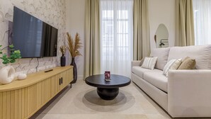 Un salon moderne avec un téléviseur à écran plat, une table basse ronde, un canapé beige et une console en bois.