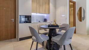 A modern kitchen with a central island, four grey upholstered chairs, and a round table.