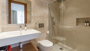 A modern bathroom with a large sink, mirror, and shower.