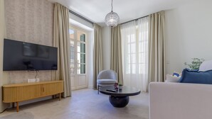 Una sala de estar moderna con una televisión de pantalla plana, una mesa de centro redonda, un sillón gris y un sofá.