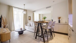 Una sala de estar moderna con comedor, un sofá, una mesa de centro y una araña.