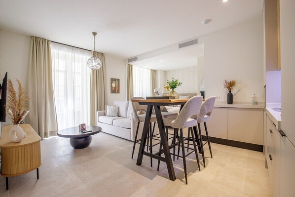 Una sala de estar moderna con comedor, un sofá, una mesa de centro y una araña.