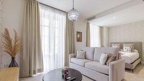 Una habitación de hotel moderna con un sofá, una mesa redonda de centro y una cama con almohadas a juego.