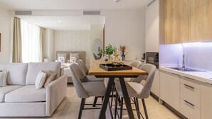 Una sala de estar moderna con un sofá, una mesa de comedor y sillas. Hay una zona de cocina con un fregadero y armarios.