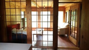 A wooden interior with a bed, a chair, and a window.