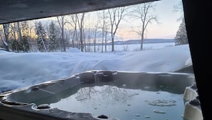A hot tub with a snowy landscape visible through the window.